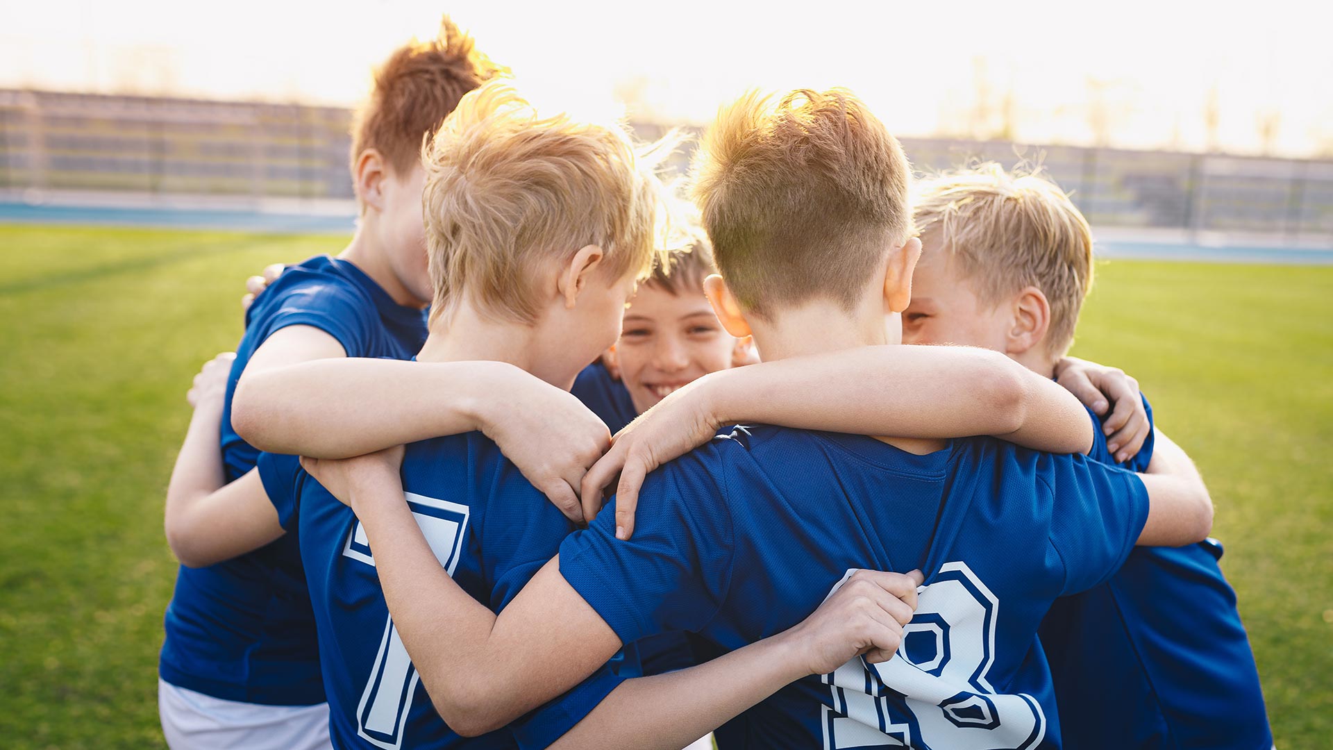 Happy kids in elementary school sports team celebrating soccer succes in tournament final game. Children soccer team team gathering together in a circle, to strategize, motivate and celebrate